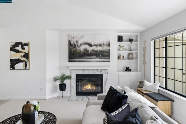 living room featuring built in features, light carpet, and vaulted ceiling