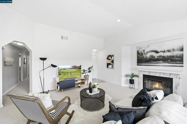 living room with a premium fireplace, light colored carpet, and vaulted ceiling