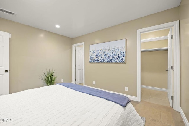 bedroom with light tile patterned flooring, a walk in closet, and a closet