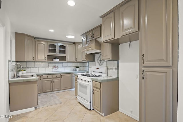 kitchen featuring sink, tile counters, white gas range, and custom exhaust hood