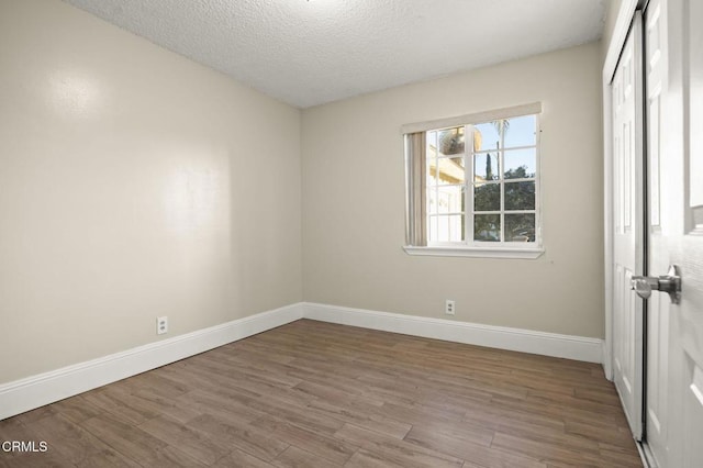 spare room featuring hardwood / wood-style flooring and a textured ceiling