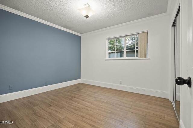 empty room with crown molding, a textured ceiling, and light wood-type flooring