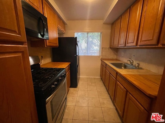 kitchen featuring black appliances, backsplash, light tile patterned flooring, and sink