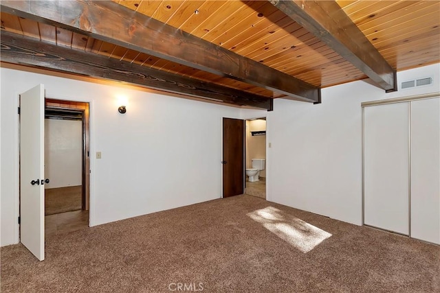 unfurnished bedroom featuring beamed ceiling, ensuite bathroom, carpet floors, and wooden ceiling