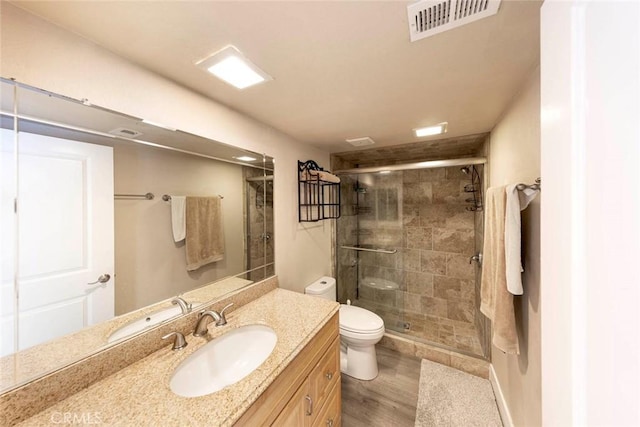 bathroom with a shower with shower door, toilet, wood-type flooring, and vanity