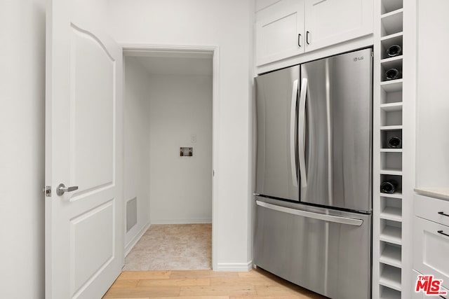 kitchen with stainless steel refrigerator, white cabinets, and light wood-type flooring