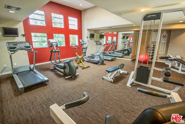 workout area with a towering ceiling and dark carpet