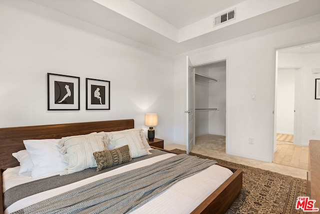 bedroom featuring a spacious closet, a closet, and wood-type flooring