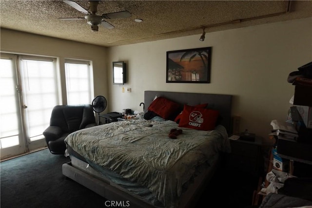 bedroom with ceiling fan, dark carpet, a textured ceiling, and access to outside