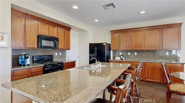 kitchen featuring sink, an island with sink, and black appliances