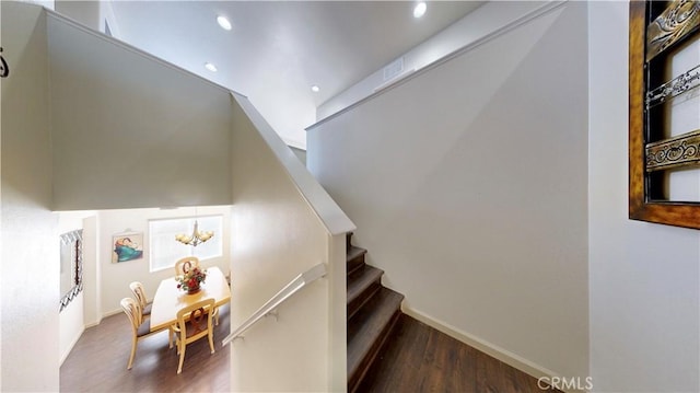 stairs with hardwood / wood-style floors and a notable chandelier