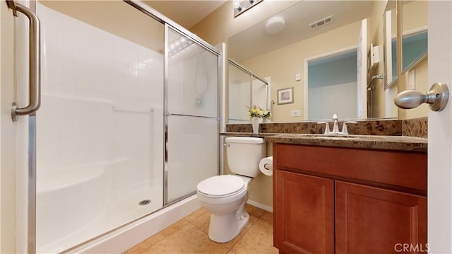 bathroom with tile patterned floors, a shower with door, vanity, and toilet