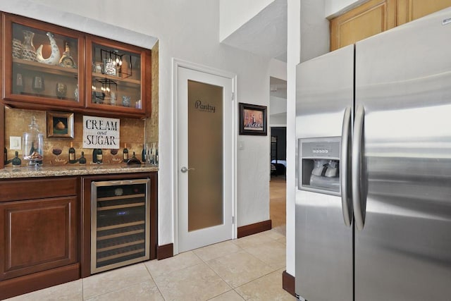 bar with stainless steel fridge, backsplash, light stone counters, beverage cooler, and light tile patterned floors