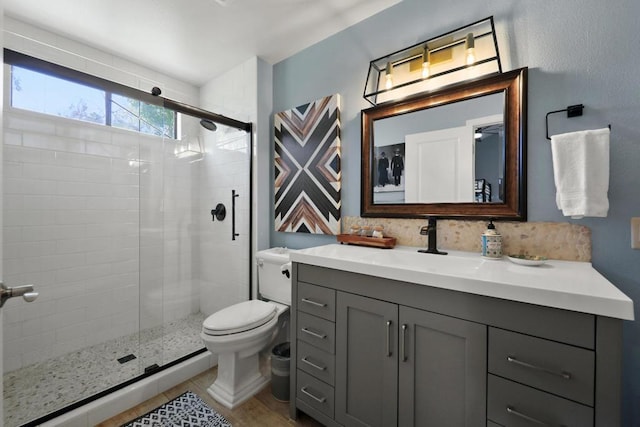 bathroom featuring a shower with door, vanity, and toilet