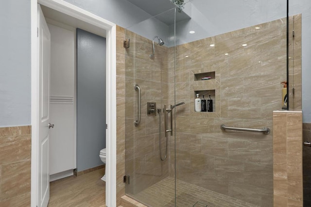 bathroom featuring hardwood / wood-style flooring, a shower with door, and toilet