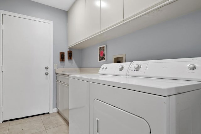 laundry area featuring washer and dryer, light tile patterned flooring, and cabinets