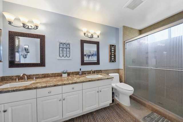 bathroom featuring tile patterned floors, vanity, toilet, and a shower with door