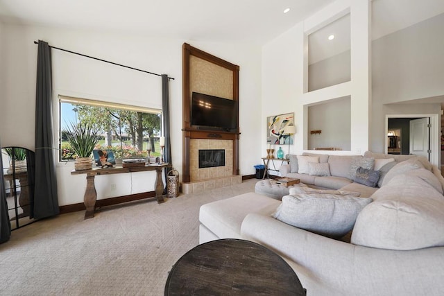 living room featuring carpet, high vaulted ceiling, and a tiled fireplace