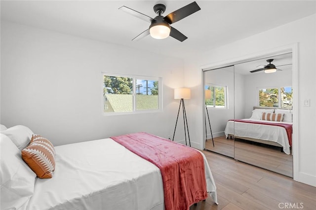 bedroom with ceiling fan, a closet, multiple windows, and light hardwood / wood-style flooring