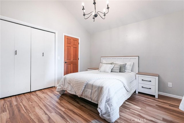 bedroom featuring a closet, an inviting chandelier, high vaulted ceiling, and light hardwood / wood-style flooring