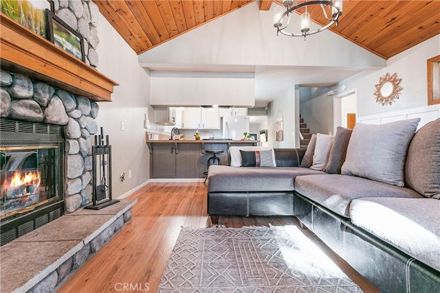 living room with a stone fireplace, high vaulted ceiling, wooden ceiling, and light wood-type flooring