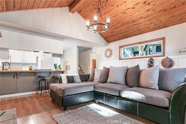 living room featuring wood ceiling, sink, beam ceiling, light hardwood / wood-style flooring, and a notable chandelier