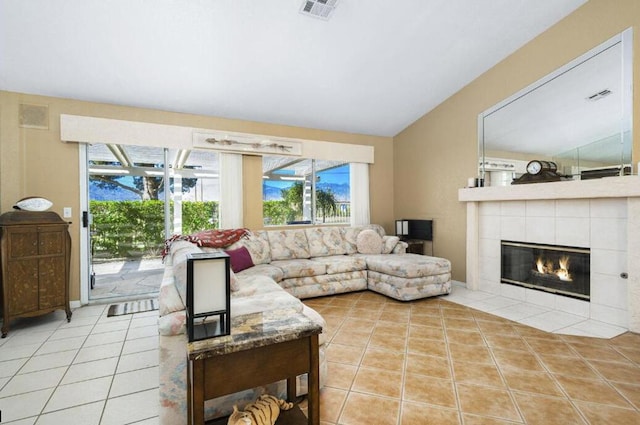 living room featuring a tile fireplace, lofted ceiling, and light tile patterned flooring