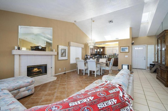 living room featuring lofted ceiling, a fireplace, light tile patterned floors, and a chandelier