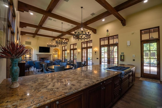 kitchen with dark wood-style floors, french doors, a fireplace, stainless steel gas stovetop, and coffered ceiling