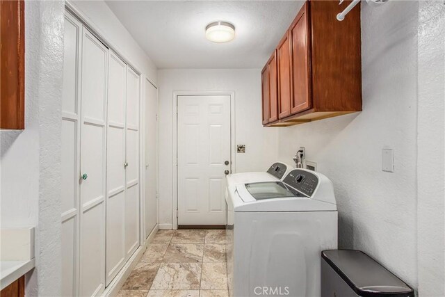 clothes washing area with washing machine and clothes dryer and cabinets