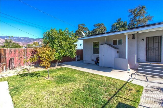 view of yard with a mountain view, a storage shed, a patio area, and central air condition unit