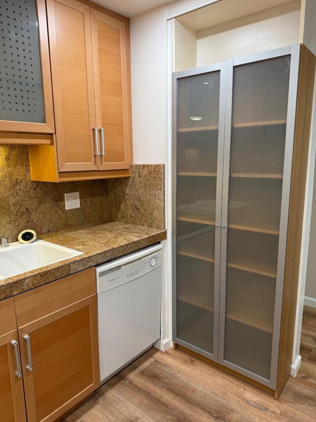 kitchen featuring white dishwasher, sink, tasteful backsplash, and light wood-type flooring