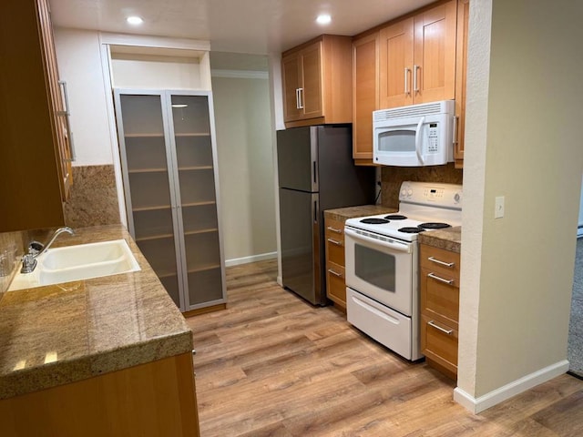 kitchen featuring sink, white appliances, light hardwood / wood-style flooring, and backsplash