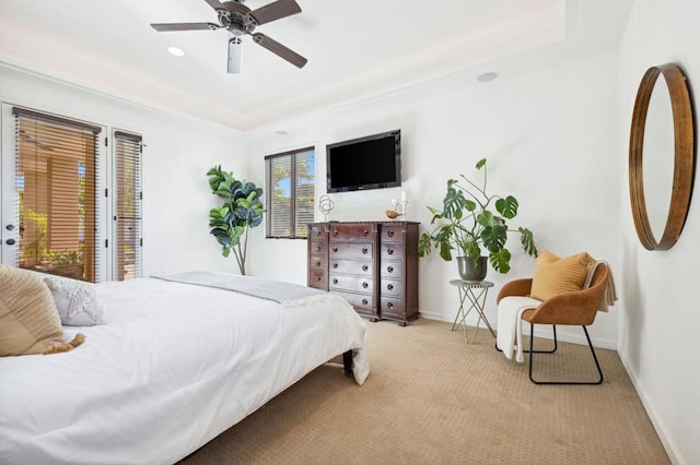 bedroom featuring a raised ceiling, light colored carpet, and ceiling fan