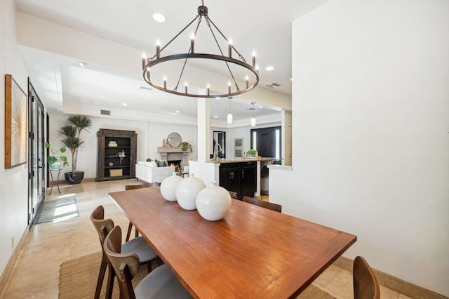 tiled dining area featuring an inviting chandelier, sink, and a raised ceiling