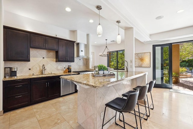 kitchen with sink, light stone counters, stainless steel dishwasher, a kitchen island, and pendant lighting