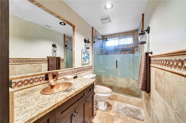 bathroom with vanity, a shower with shower door, tile walls, and toilet