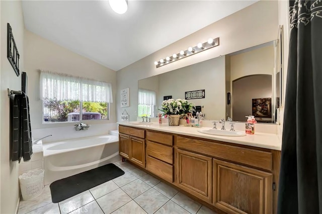 bathroom featuring a bathing tub, tile patterned flooring, vanity, and vaulted ceiling