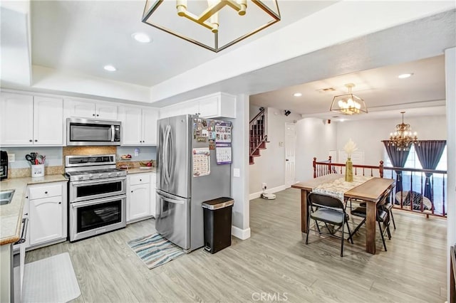 kitchen with light hardwood / wood-style flooring, white cabinets, and appliances with stainless steel finishes