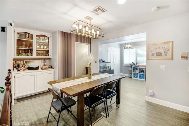 dining room with light wood-type flooring and a chandelier