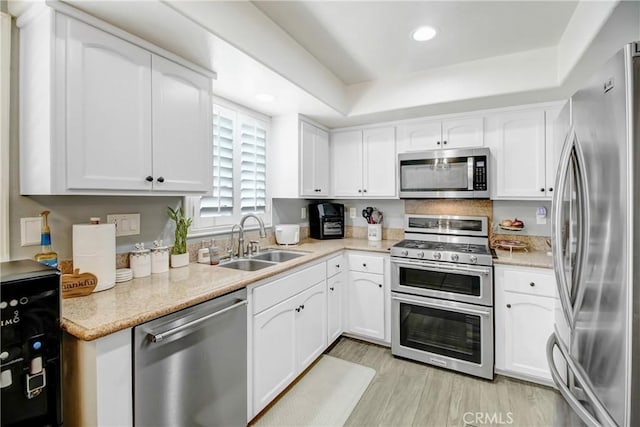 kitchen featuring a raised ceiling, sink, white cabinets, and appliances with stainless steel finishes