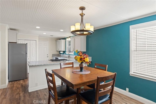 dining area featuring crown molding, dark hardwood / wood-style flooring, and sink