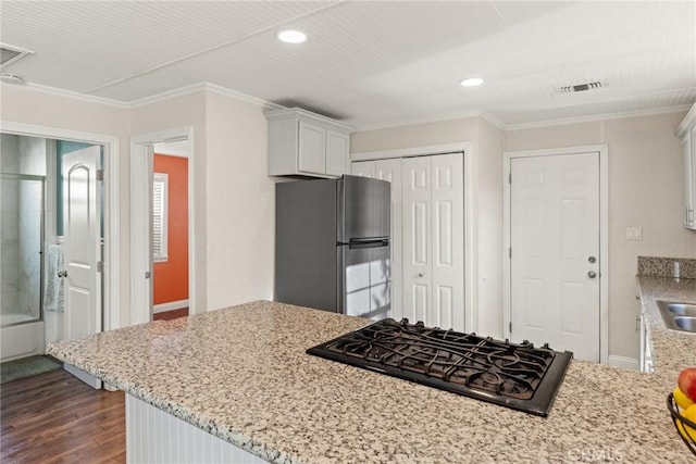 kitchen featuring light stone countertops, ornamental molding, black gas cooktop, white cabinets, and stainless steel refrigerator