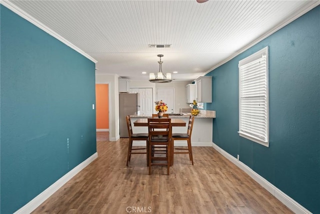 dining space with hardwood / wood-style floors, a chandelier, and ornamental molding