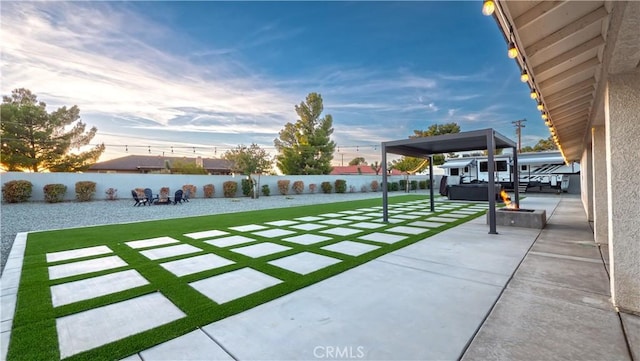 patio terrace at dusk featuring a fire pit and a yard