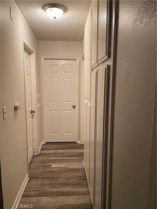 hall with a textured ceiling and dark wood-type flooring