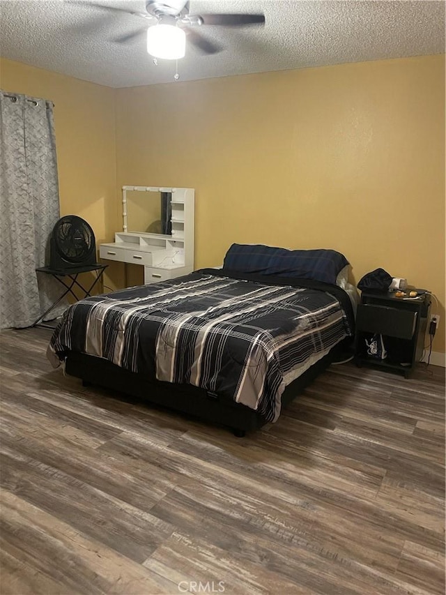 bedroom with a textured ceiling, ceiling fan, and dark wood-type flooring