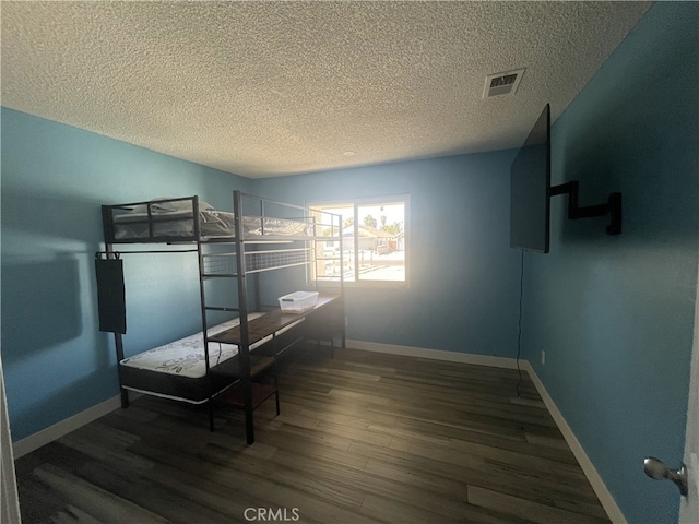 bedroom with a textured ceiling and dark hardwood / wood-style flooring