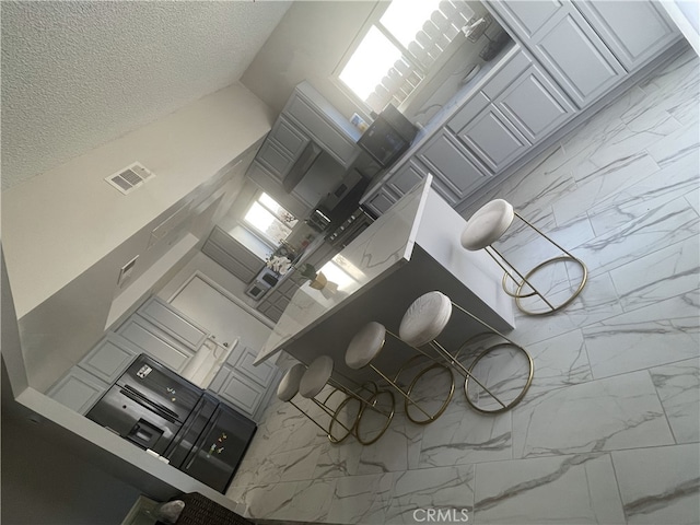 interior space with a kitchen breakfast bar, kitchen peninsula, white cabinets, and a textured ceiling