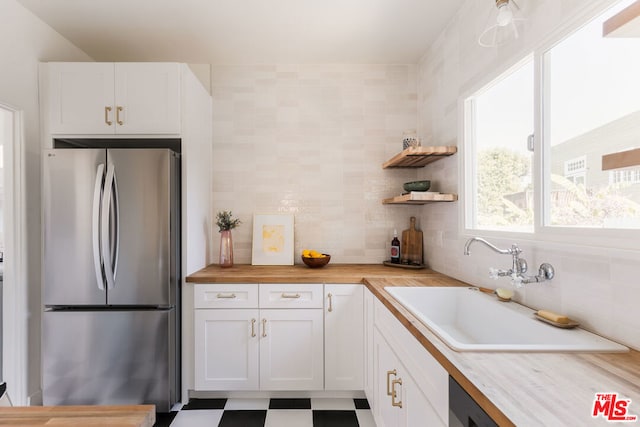 kitchen with white cabinets, sink, stainless steel refrigerator, and wooden counters